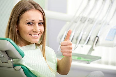 smiling woman at dental office giving thumbs up